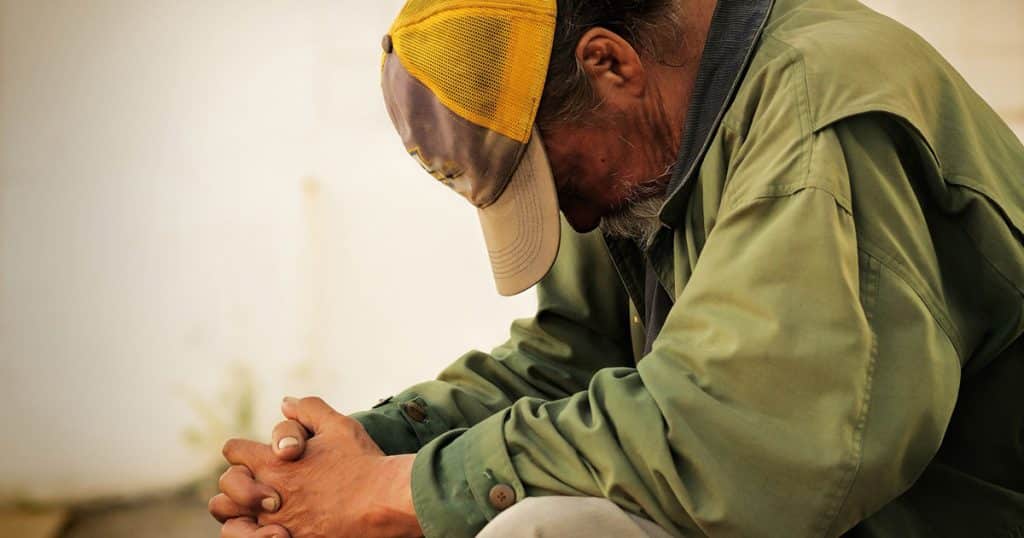 Homeless person praying. Homeless shelter post.